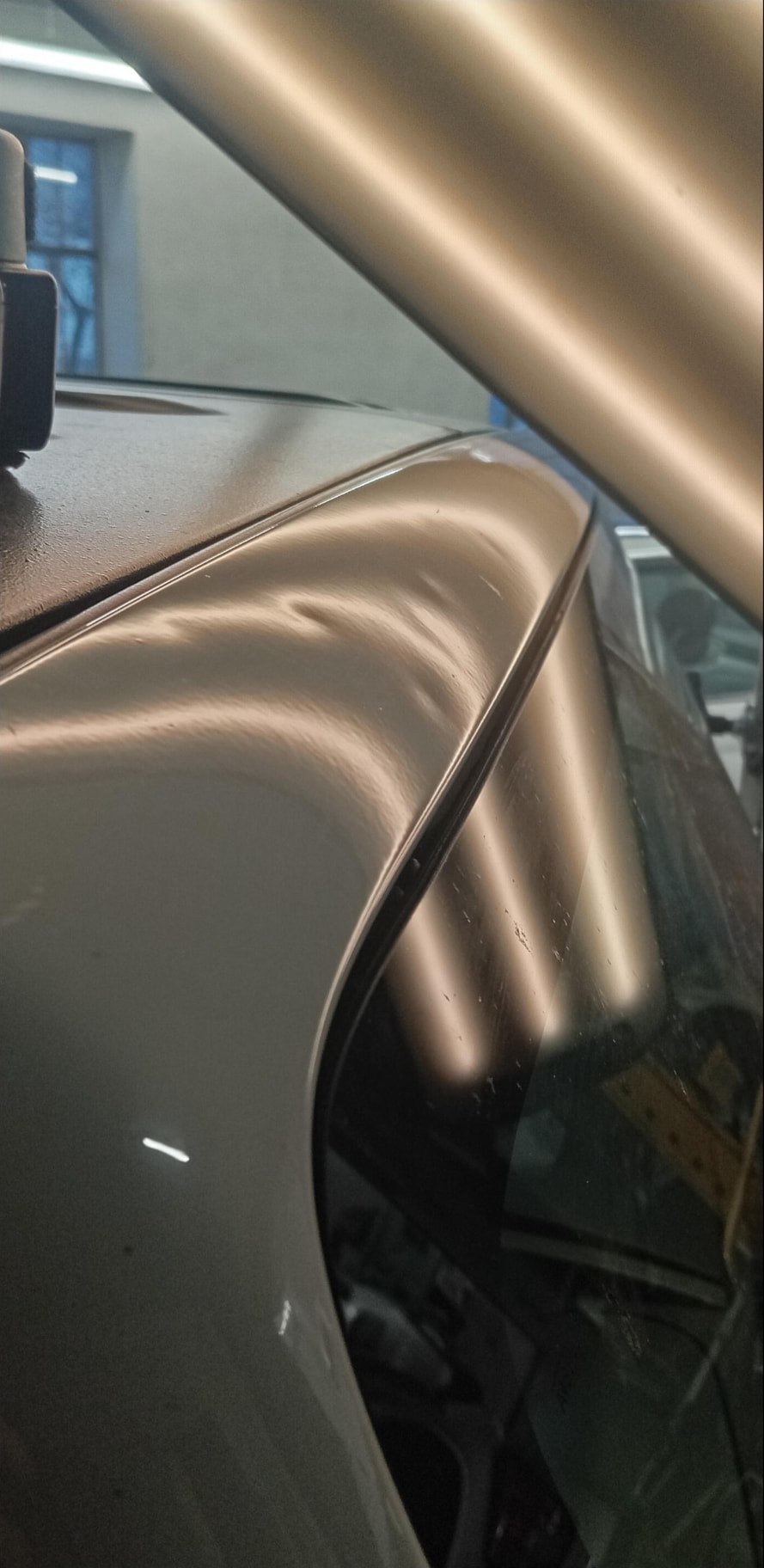 Tetto e montante di auto beige con ammaccatura da grandine prima del PDR