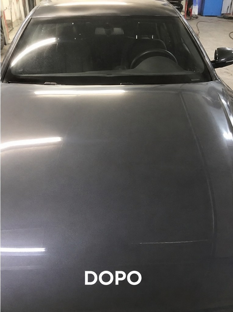 Cofano dell'auto grigia dopo la riparazione PDR dei bolli da grandine, vernice originale intatta