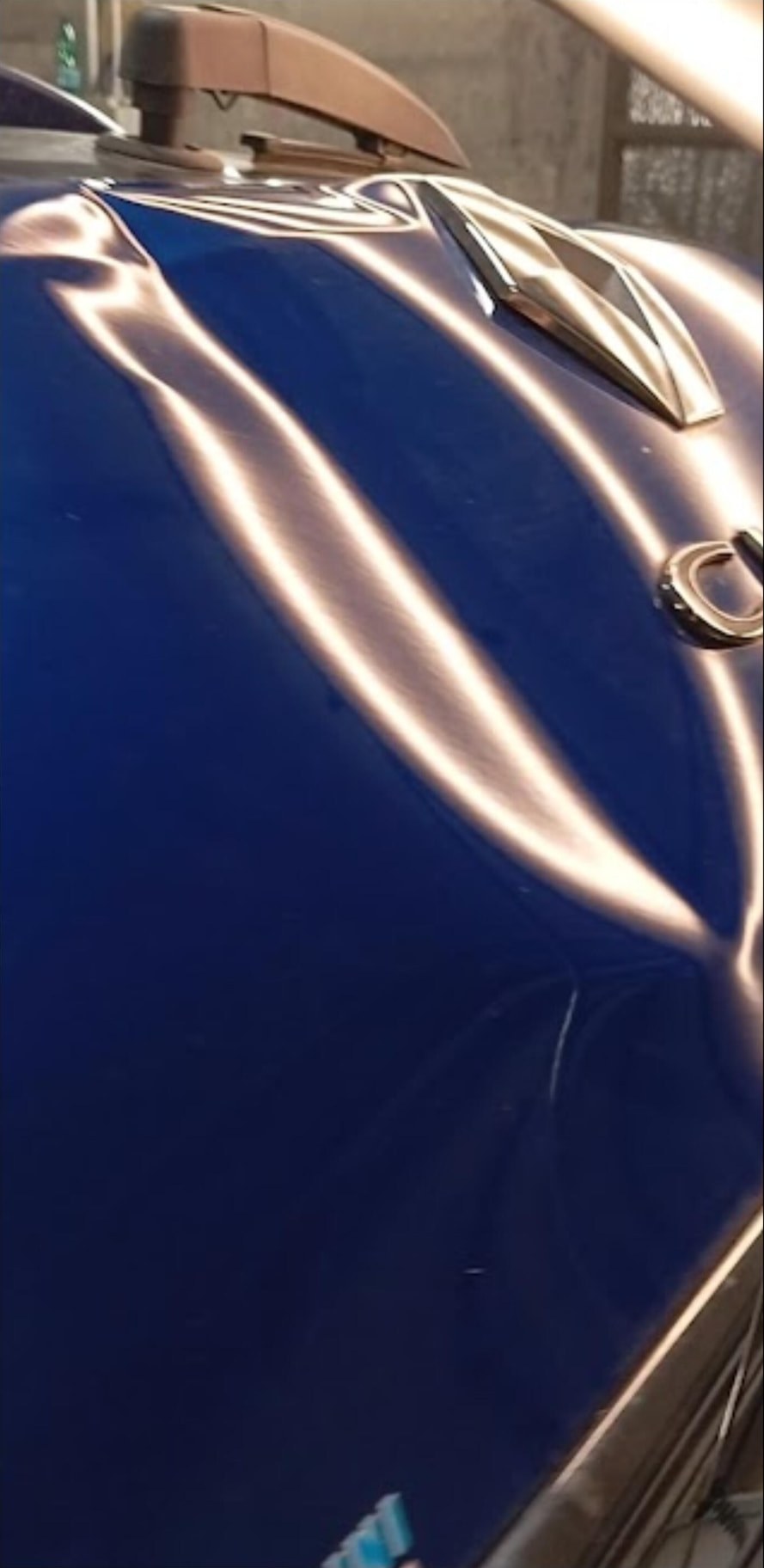 Cofano blu con ammaccatura da grandine prima della riparazione grandine